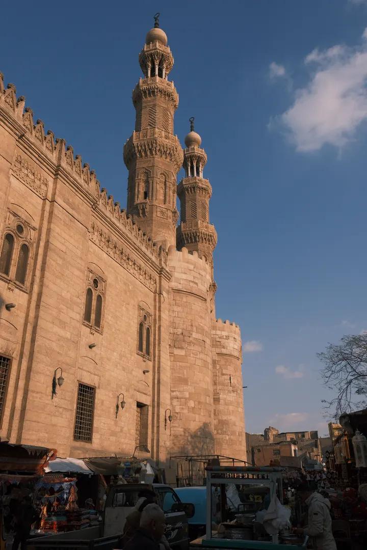 Historic Cairo street life beneath stone minarets